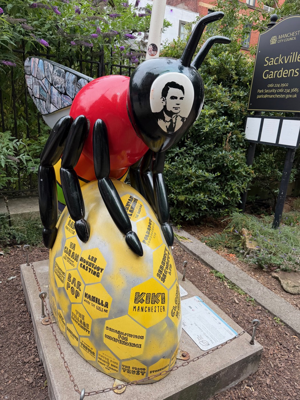 A bee sculpture in Sackville Gardens with Alan Turing's portrait on its head and a honeycomb of community names painted on its body